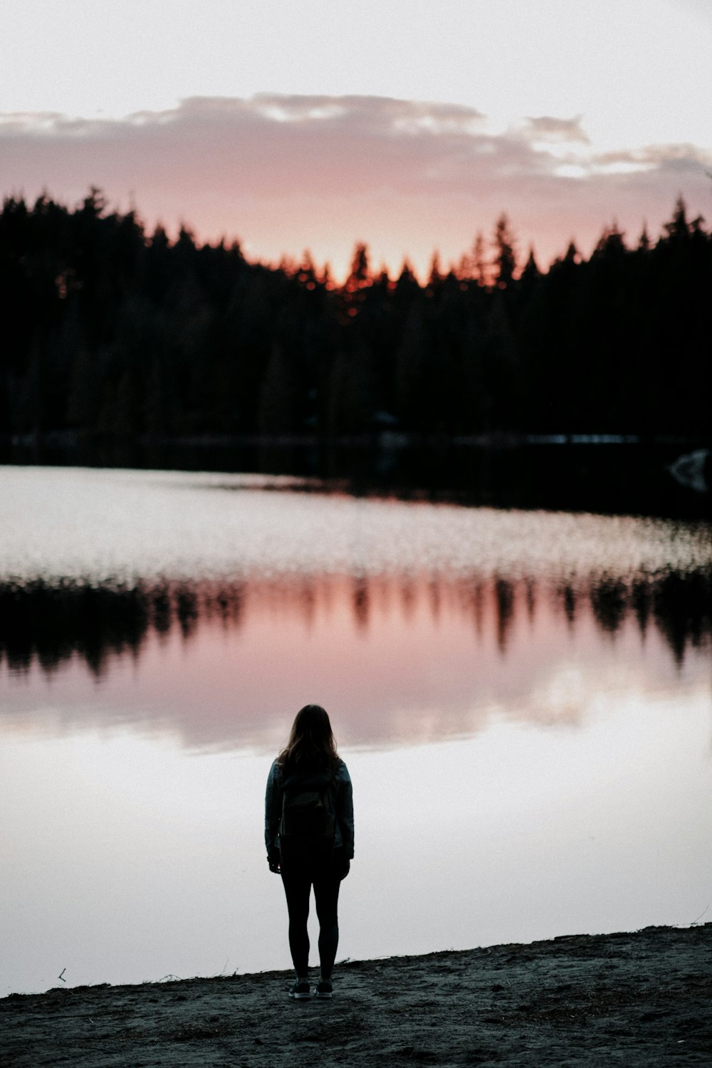 silhouette photography of woman standing beside body of water