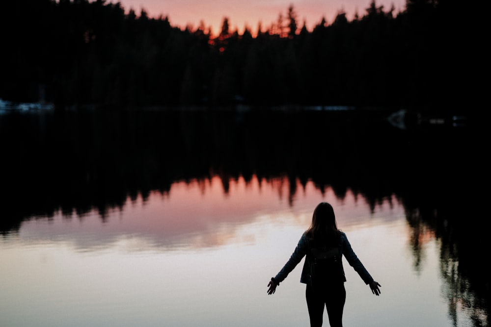 silhouette of person standing beside body of water
