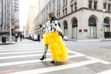 A candid shot of a confident woman walking down a city street in a chic yellow posh ensemble.