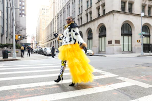 Model walking down a city street wearing layered streetwear with a mix of textures and bold colors.