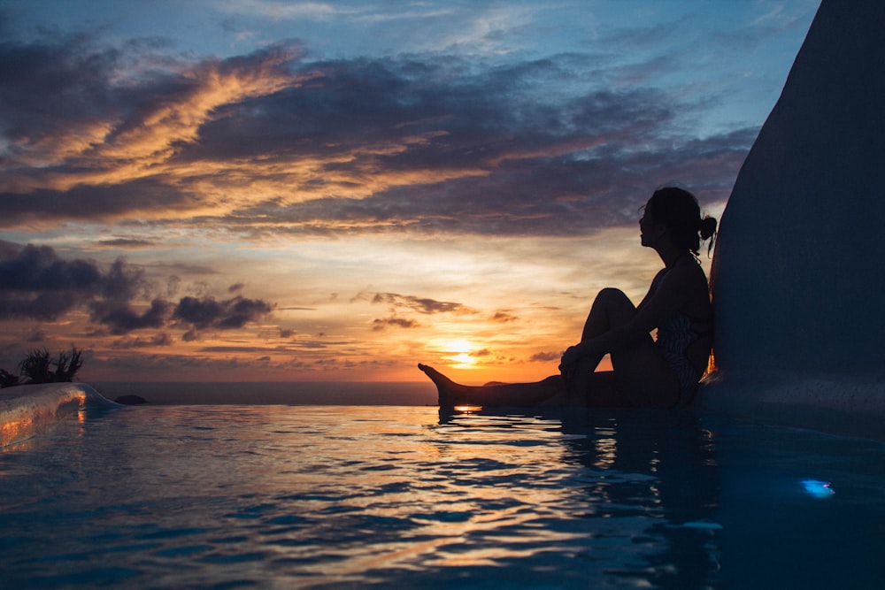 woman sitting on pool during daytime