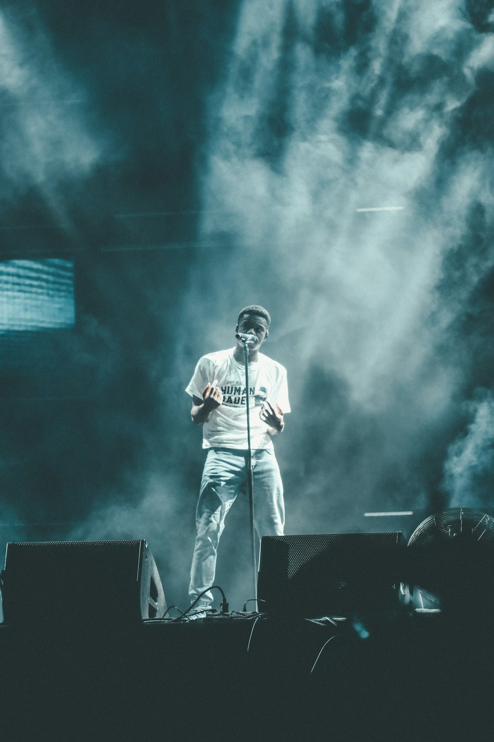 man in white shirt singing on stage