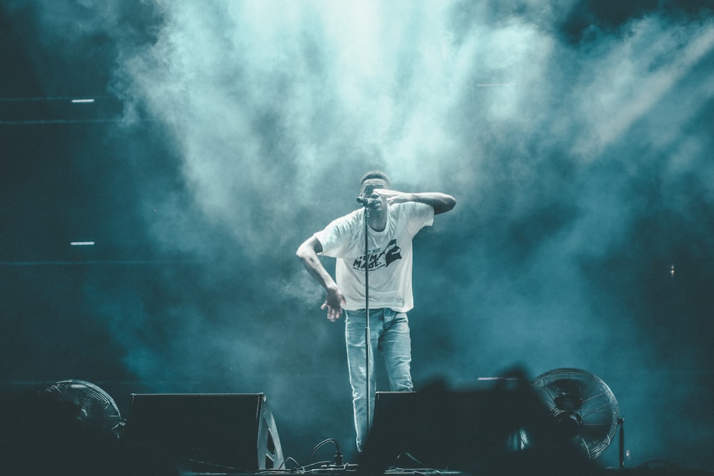 man performing on stage near microphone