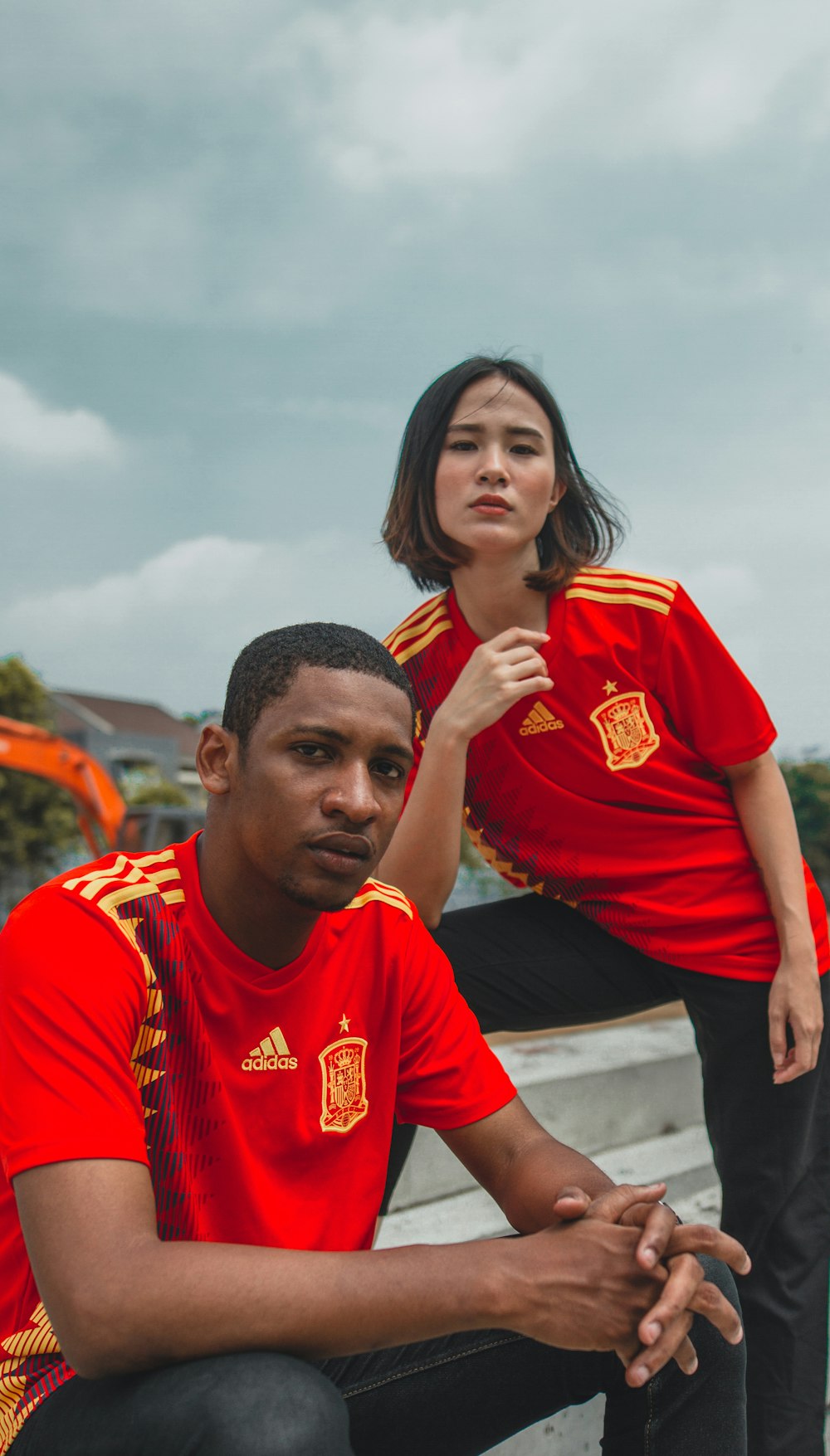 woman wearing red and yellow shirt beside man wearing red and yellow adidas shirts