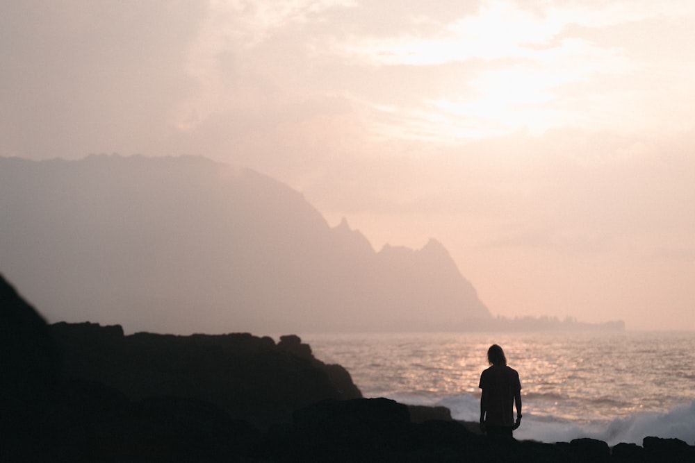 person standing in seashore during golden hour