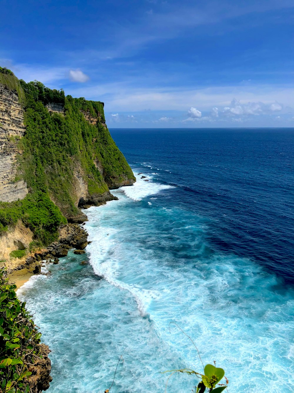 cliff and body of water under blue sky during daytime