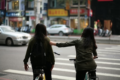 Instructor guiding a student on a two-wheeler in a calm urban setting.