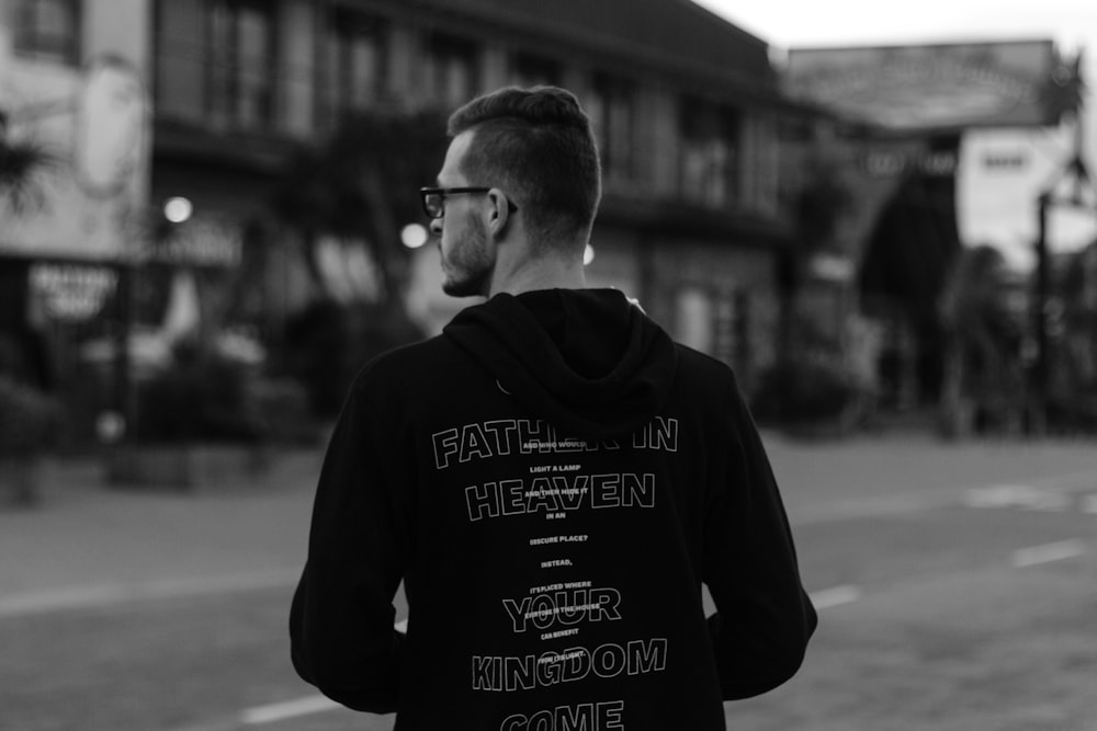 grayscale photography of man in hoodie standing front of road
