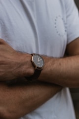 Close-up of a stylish gentleman wearing a crisp white shirt and a sleek leather watch.