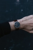 Elegant wrist wearing a classic watch against a dark, minimalist background.