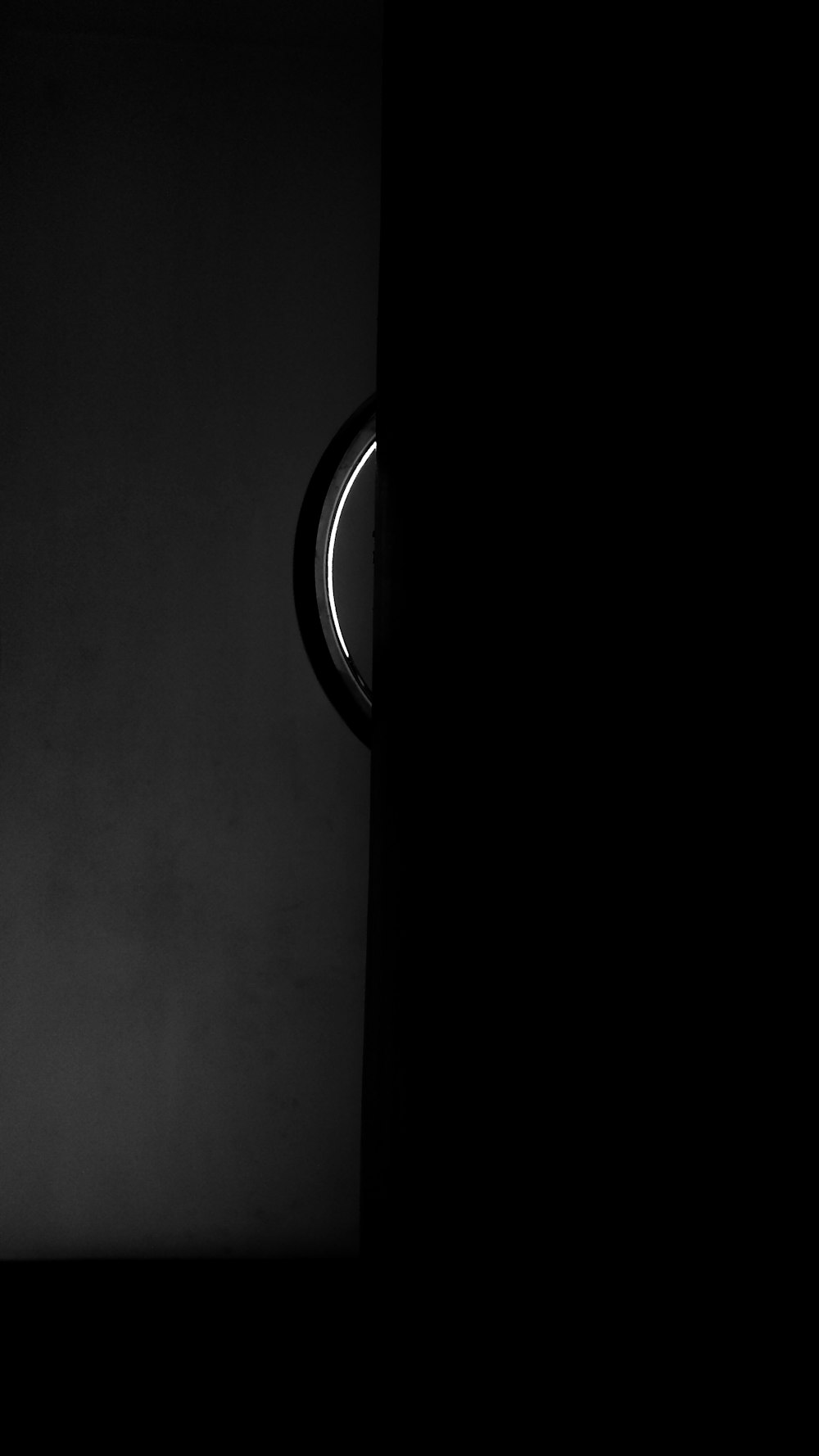 a black and white photo of a clock in a dark room