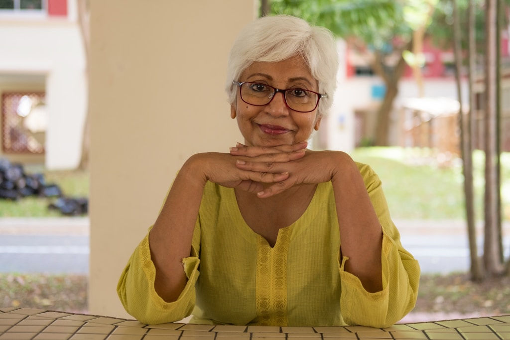 smiling woman sitting front of table considering aging in place definition