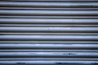Technician inspecting a metallic shutter with tools in hand.