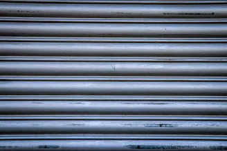 Close-up of a shiny, newly installed metallic shutter on a storefront during the day.