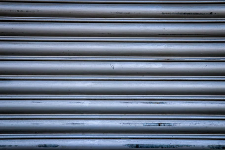 Close-up of a shiny, newly installed metallic shutter on a storefront during the day.