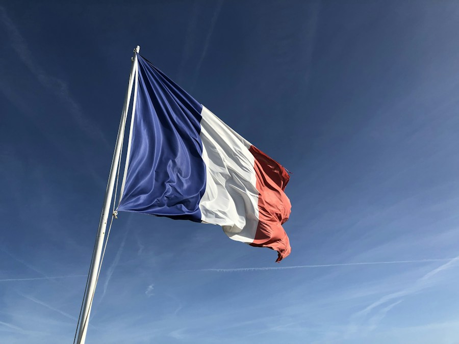 Drapeau français flottant au sommet d’un mât sous un ciel bleu