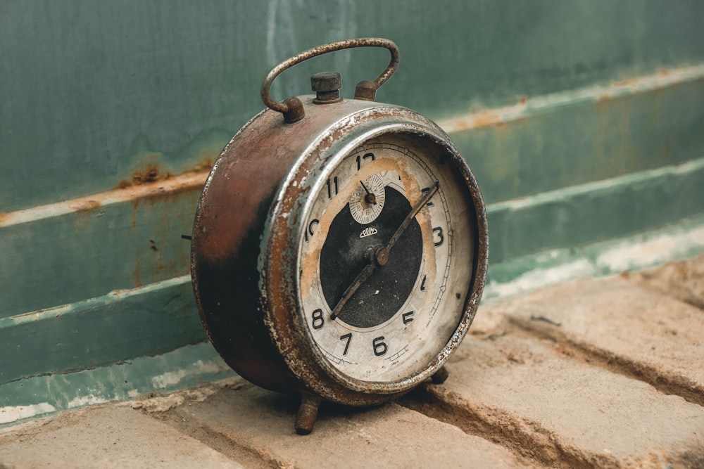 Un viejo reloj oxidado sentado en el suelo