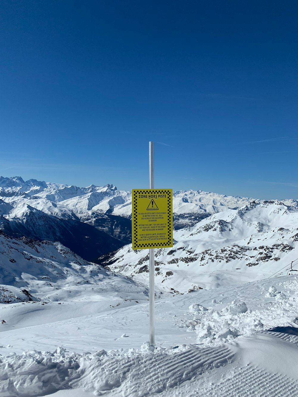 yellow and black signage at mountain covered with snow