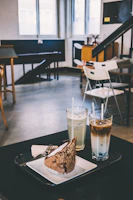 A cozy café scene featuring a steaming beverage and a slice of cake on a pastel pink surface.