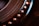Close-up of a mechanical component with circular grooves and a row of metallic rivets. The image displays intricate details and textures, emphasizing the precision in engineering. Warm lighting highlights the metallic tones, adding depth and contrast to the scene.