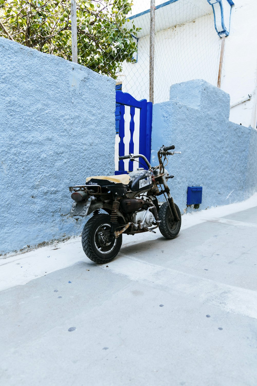 black standard motorcycle on park near blue wall