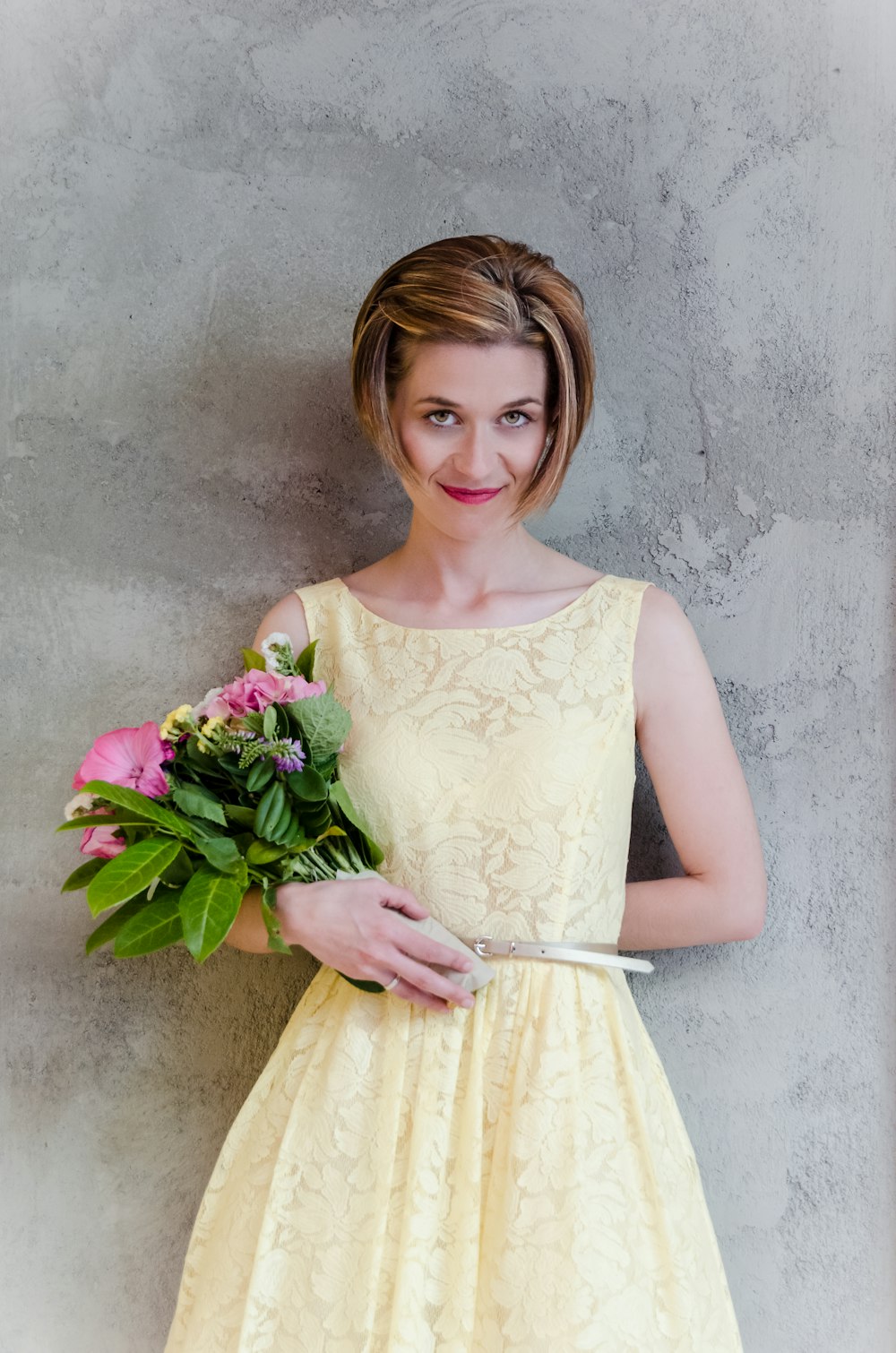 Mujer en vestido floral amarillo lleva ramo de flores rosas