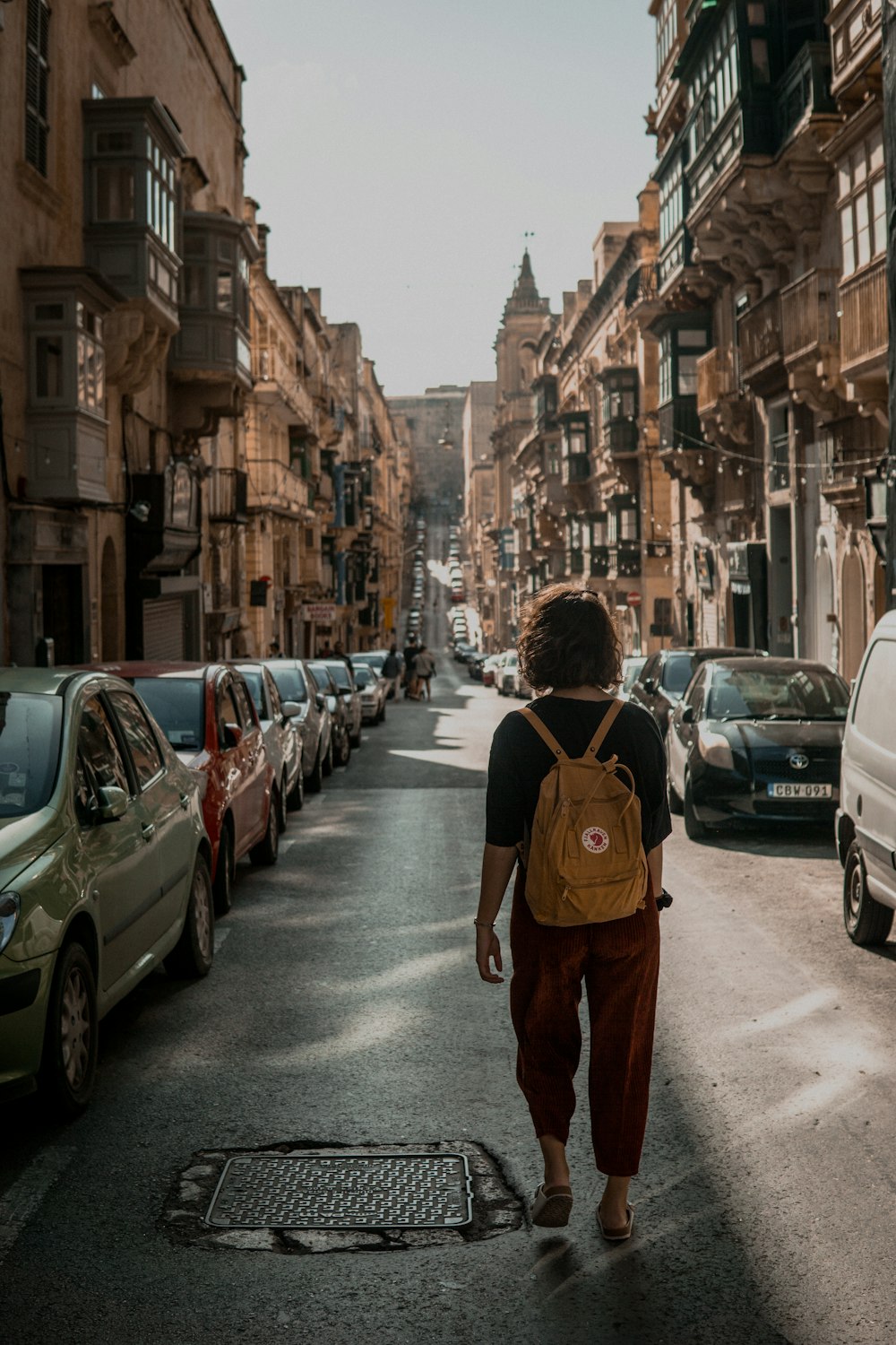 person walking between parked cars during daytime