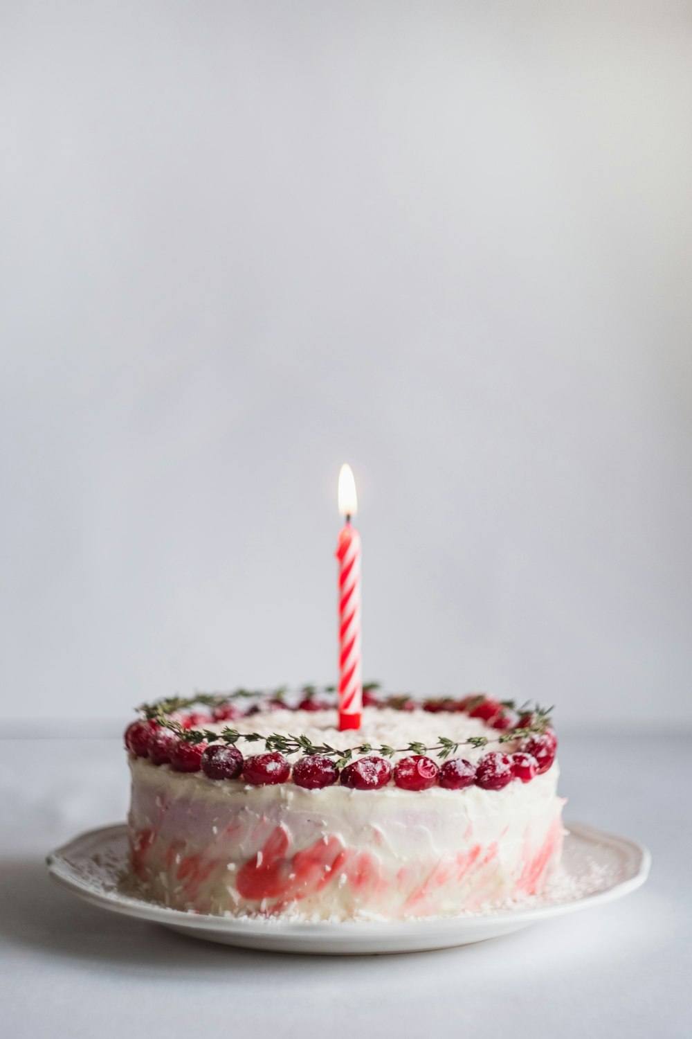 white and pink covered cake with lightened candle