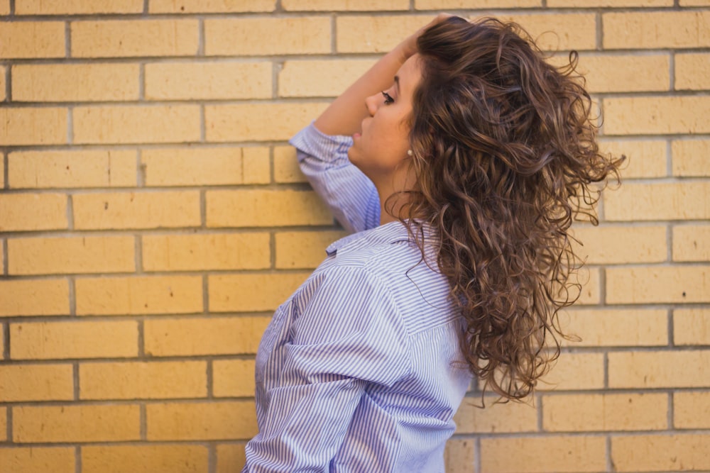 woman in gray dress shirt near brick wall