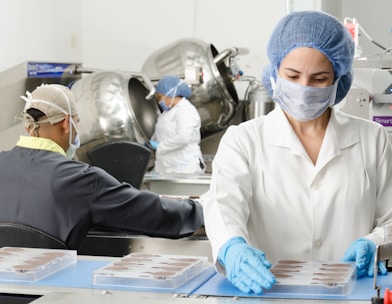 three people inside factory wearing masks and coats