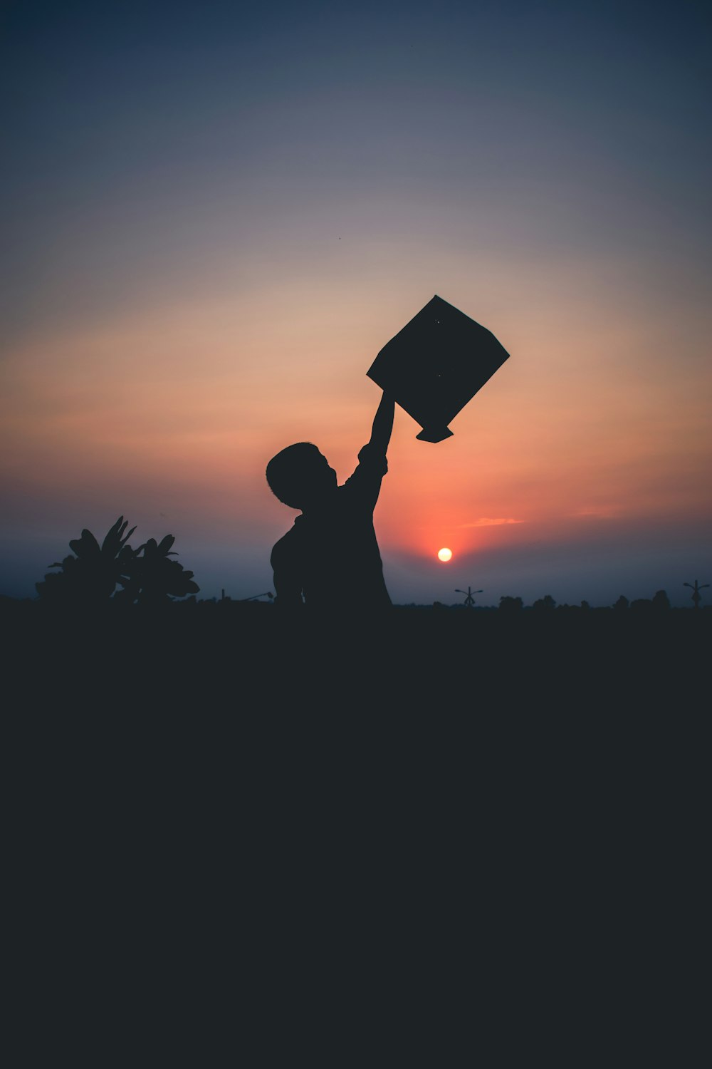 shadow of person raising right hand holding square object