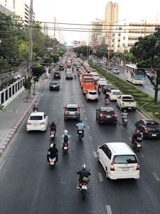 A vibrant city street with cars and motorcycles in motion.