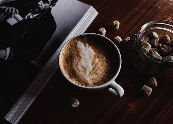 A grainy black-and-white photo of a dimly lit café corner with an open book and a steaming cup of coffee at 2am.