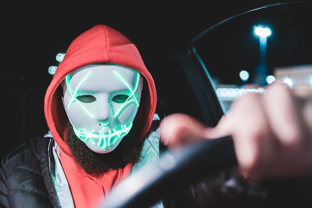 man driving vehicle wearing mask at night-time