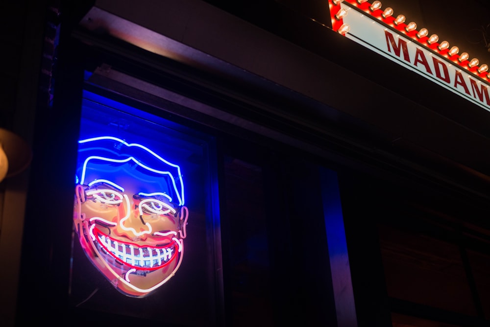 a neon sign of a man's face on the side of a building