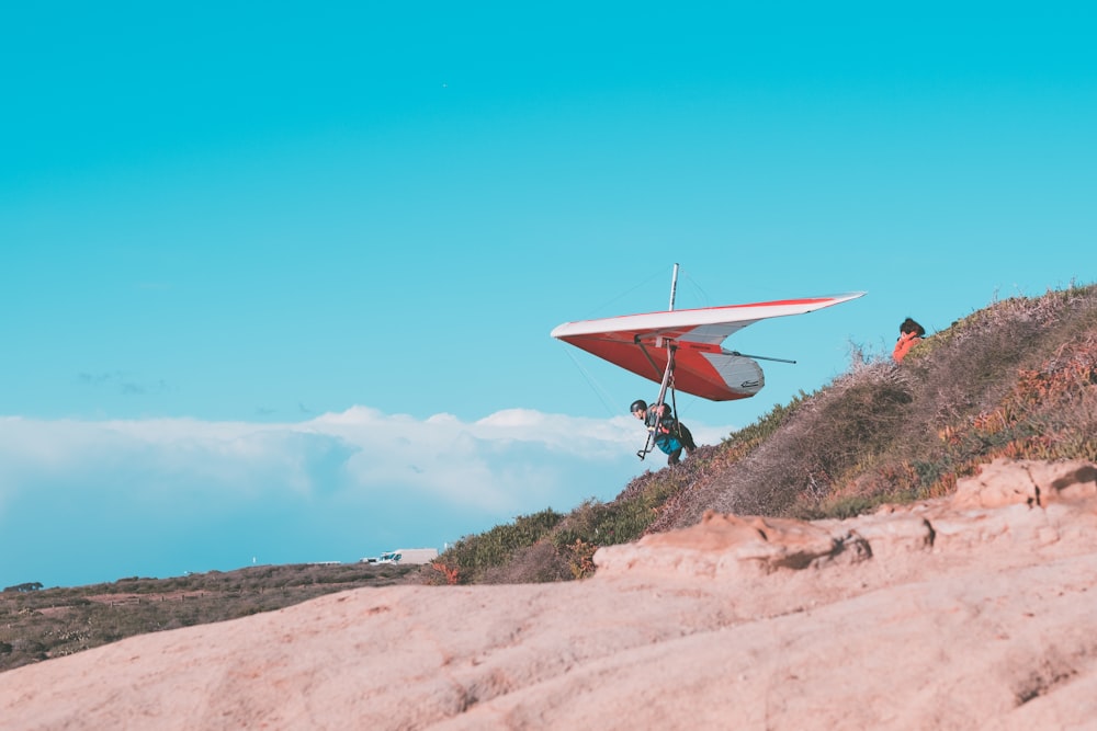 a man carrying a glider on top of a hill