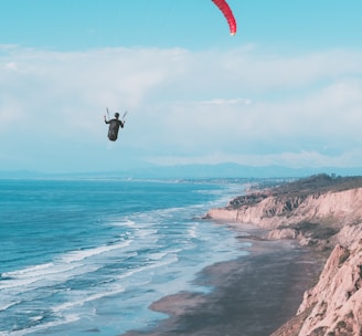 a person is parasailing over the ocean on a sunny day