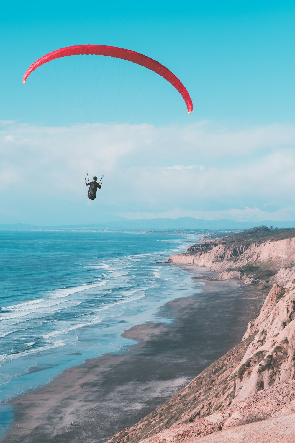 Una persona está navegando en parasailing sobre el océano en un día soleado