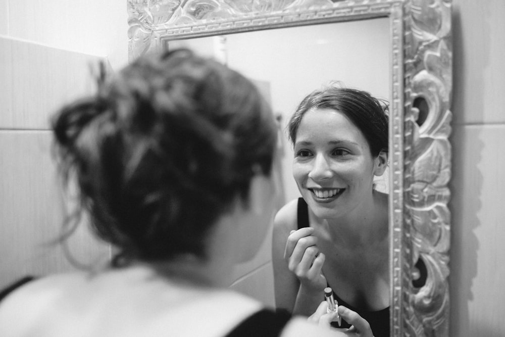 woman smiles in front of mirror