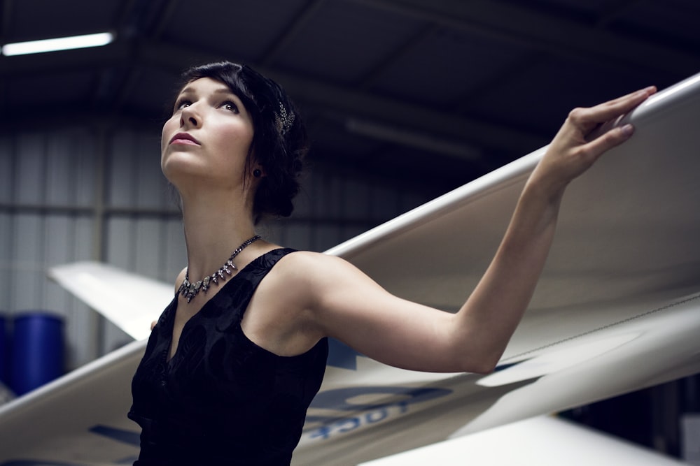 a woman in a black dress holding a white surfboard