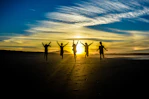 people jumping on shore front of golden hour