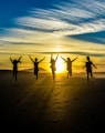 people jumping on shore front of golden hour