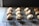 A collection of small baked goods topped with cream and orange zest is arranged in rows on a cooling rack. The baked items appear golden-brown and are placed on a dark wire rack over a wooden surface.