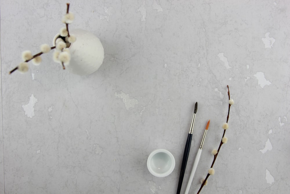 two paint brushes beside ceramic vase