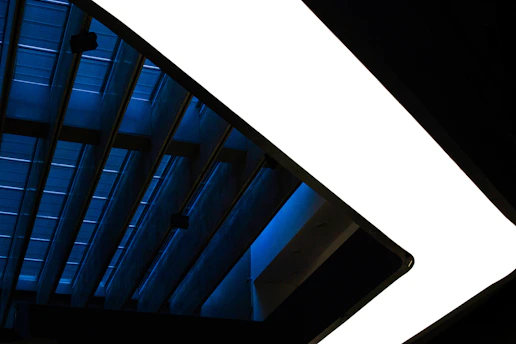 Minimalist architectural lines forming fragmented structures symbolizing narrative cracks, lit with electric blue accents.