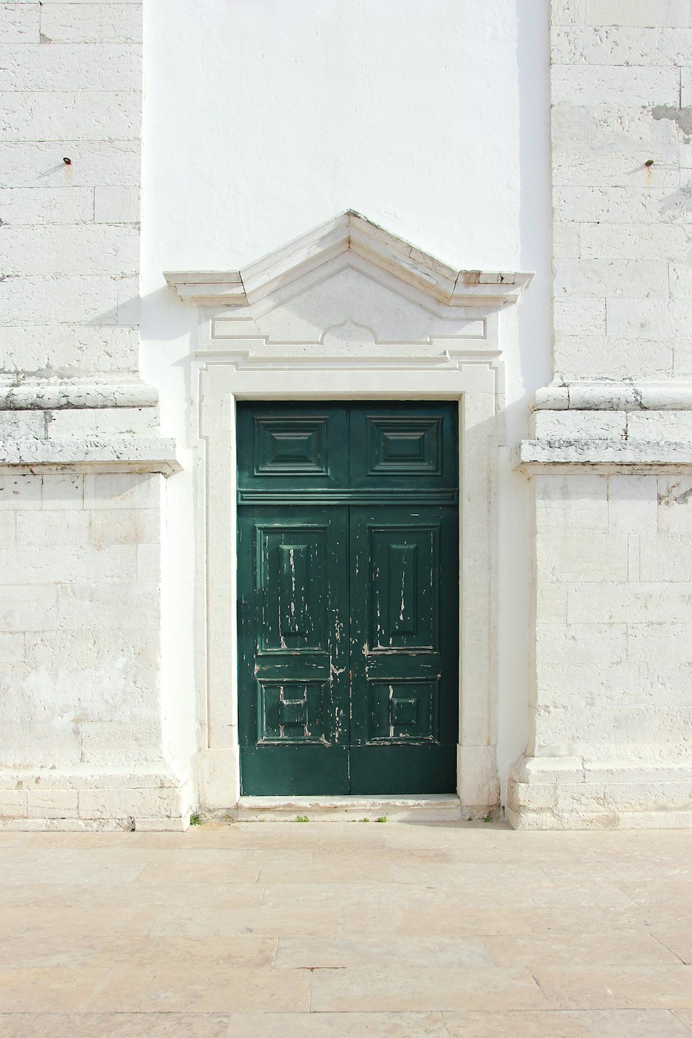 green wooden door with white wall