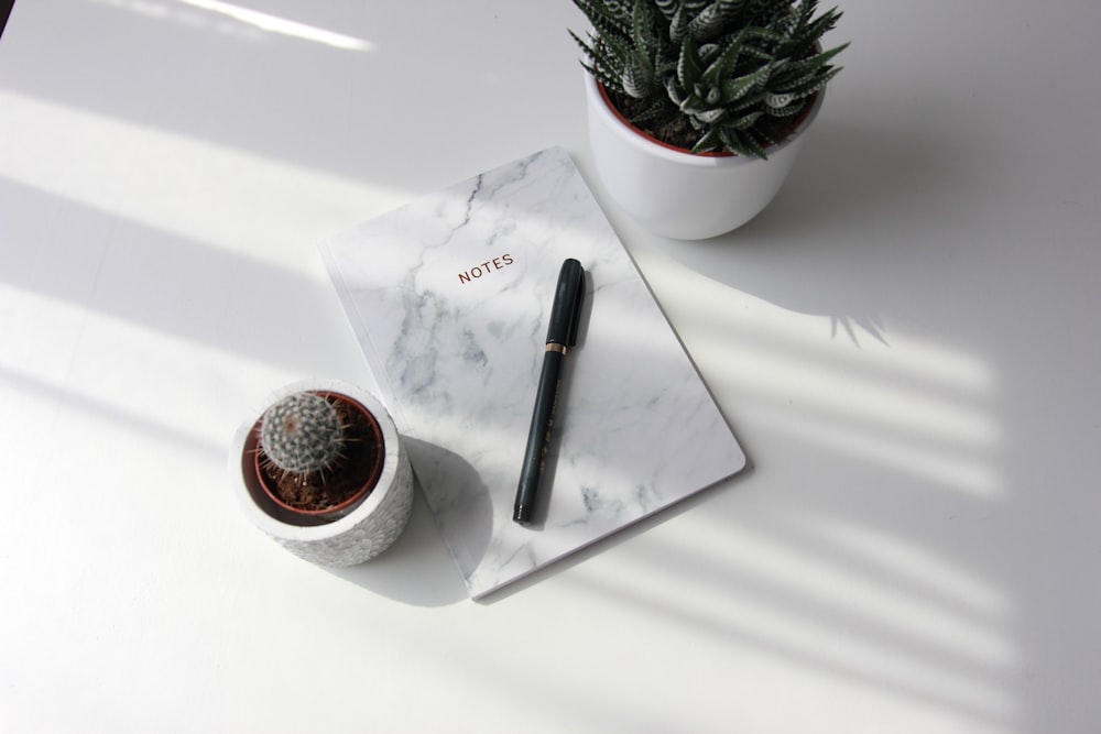 white book and black pen on table