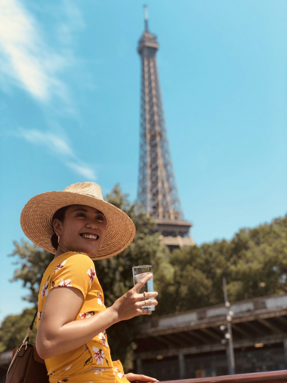 woman wearing yellow floral dress holding highball glass