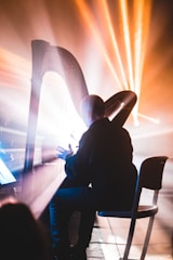 Stage shot of a harpist illuminated by soft golden light during a solo performance.