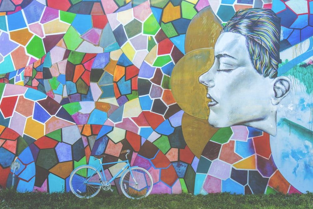 blue bike leaning beside mural wall